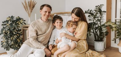Happy family of four enjoying quality time together in a cozy, plant-filled room.